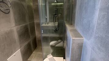 Une salle de bain moderne dotée d’une douche à parois de verre, de toilettes et d’un bidet.