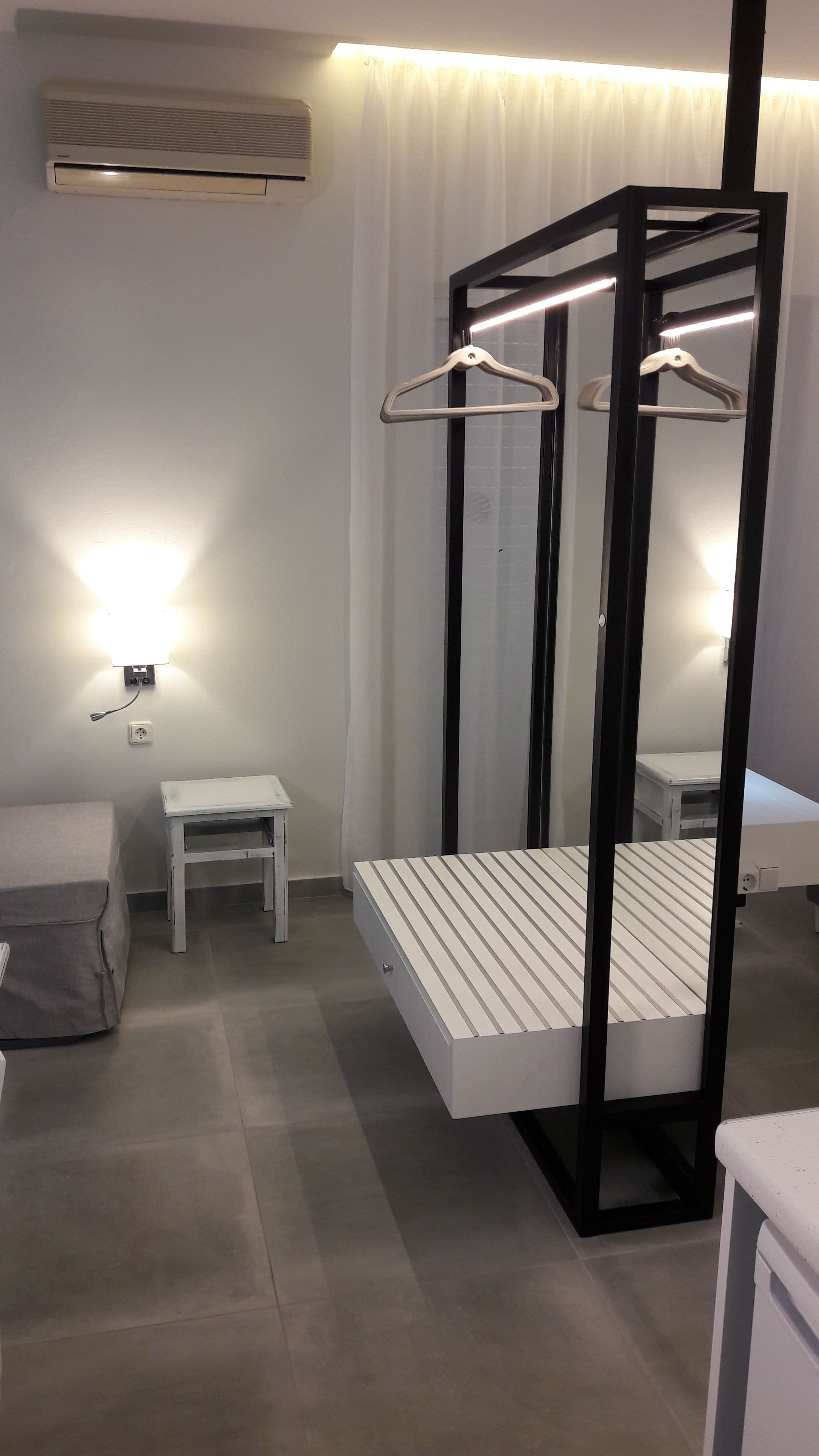 A modern bedroom with a bed, bedside table, and a wall-mounted heater.