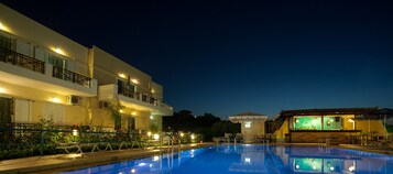 Una piscina al aire libre, sombrillas, sillones reclinables de piscina