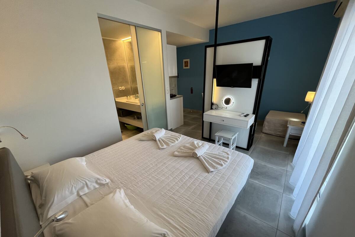 A hotel room with a bed, a desk, a mirror, and a bathroom.