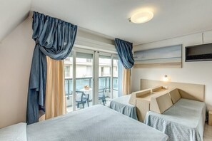 Une chambre d’hôtel avec deux lits, un balcon doté d’une table et de chaises, et un téléviseur fixé au mur.