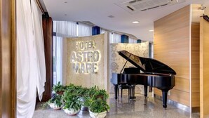 A hotel lobby with a grand piano, potted plants, and a sign reading "HOTEL ASTRO MARE". - Astromare (Jesolo)