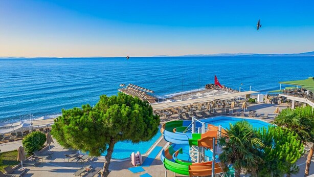 Un complexe hôtelier doté d’une piscine, de chaises longues et offrant une vue sur la mer.