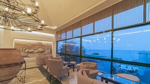 Un salon moderne doté d’une grande fenêtre donnant sur la mer, de sièges confortables et d’un luminaire décoratif au plafond.