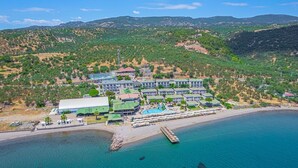 Vue aérienne d’un hôtel situé sur la côte, composé de plusieurs bâtiments, doté d’une piscine et d’une jetée qui s’avance dans la mer.