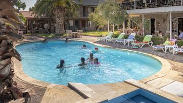 Relax by the pool surrounded by lush greenery and lounge under the shade of umbrellas.