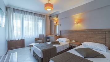 A hotel room with two beds, a desk, a chair, and a large window with curtains.