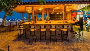 Un bar en plein air avec des murs en pierre et de nombreux tabourets.