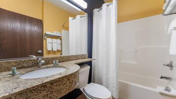 Une salle de bain avec un lavabo sur un plan de travail en granit, des toilettes, une baignoire et un rideau de douche.