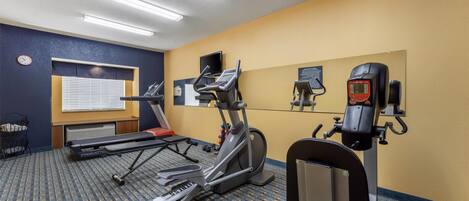 Un gimnasio con cintas de correr, elíptica y bicicleta estática.