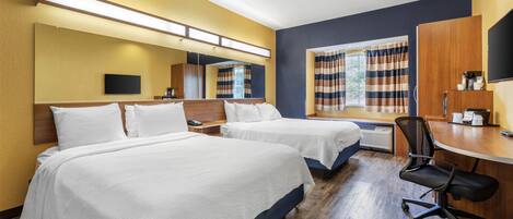 A hotel room with two beds, a desk, a chair, a TV, and a window with curtains.