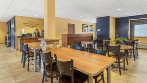 A restaurant with a stone pillar, wooden tables, and chairs. There is a sign on the wall that reads "Welcome to West Virginia Keyser." - SureStay Plus Hotel by Best Western Keyser (Keyser)