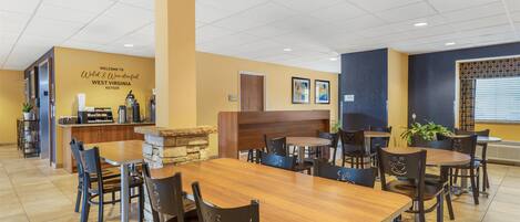 A restaurant with a counter, tables, chairs, and a wall with a welcome sign.