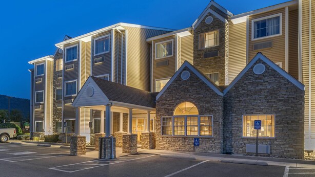 A multi-story hotel with a stone facade, multiple windows, and a covered entrance. - SureStay Plus Hotel by Best Western Keyser (Keyser)