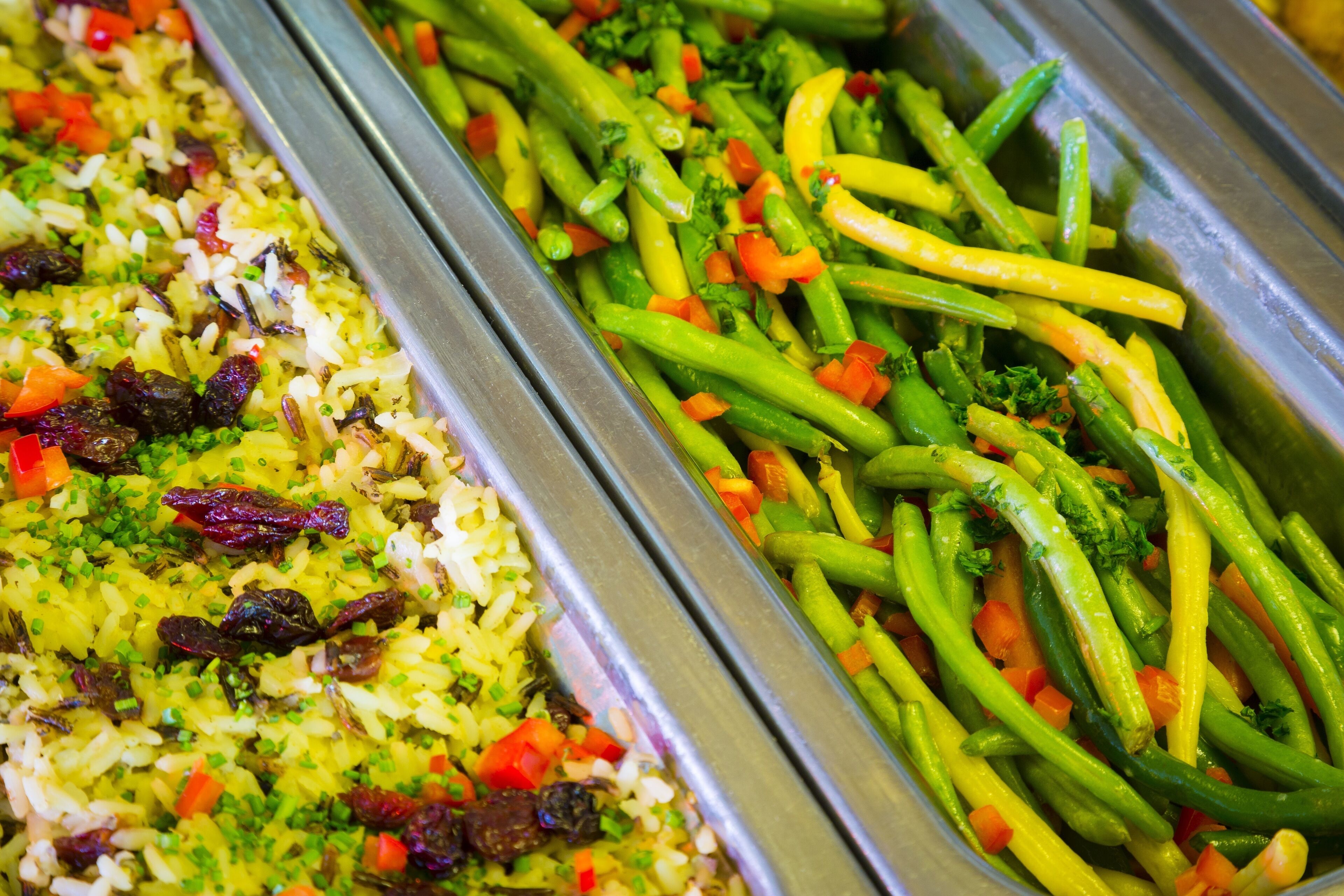 A buffet with rice, green beans, and carrots.