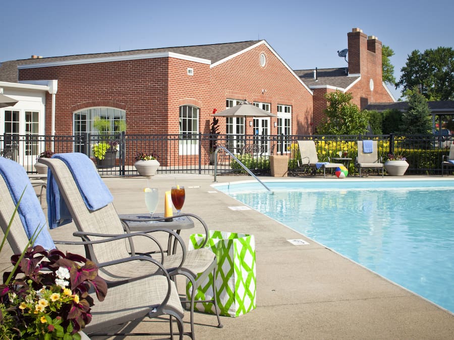 A poolside area with lounge chairs and a brick building in the background.