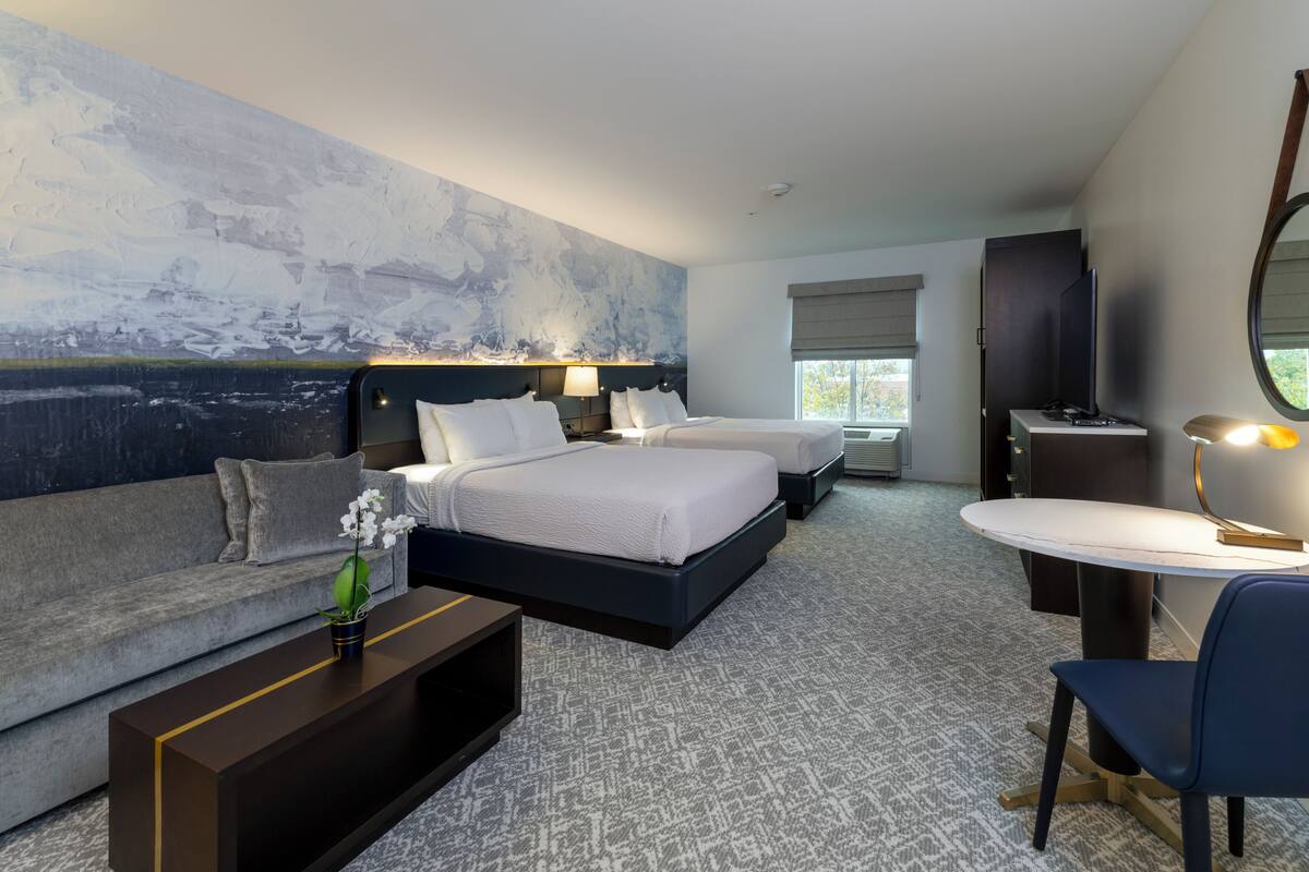 A hotel room with a large bed, a sofa, a desk, and a TV.