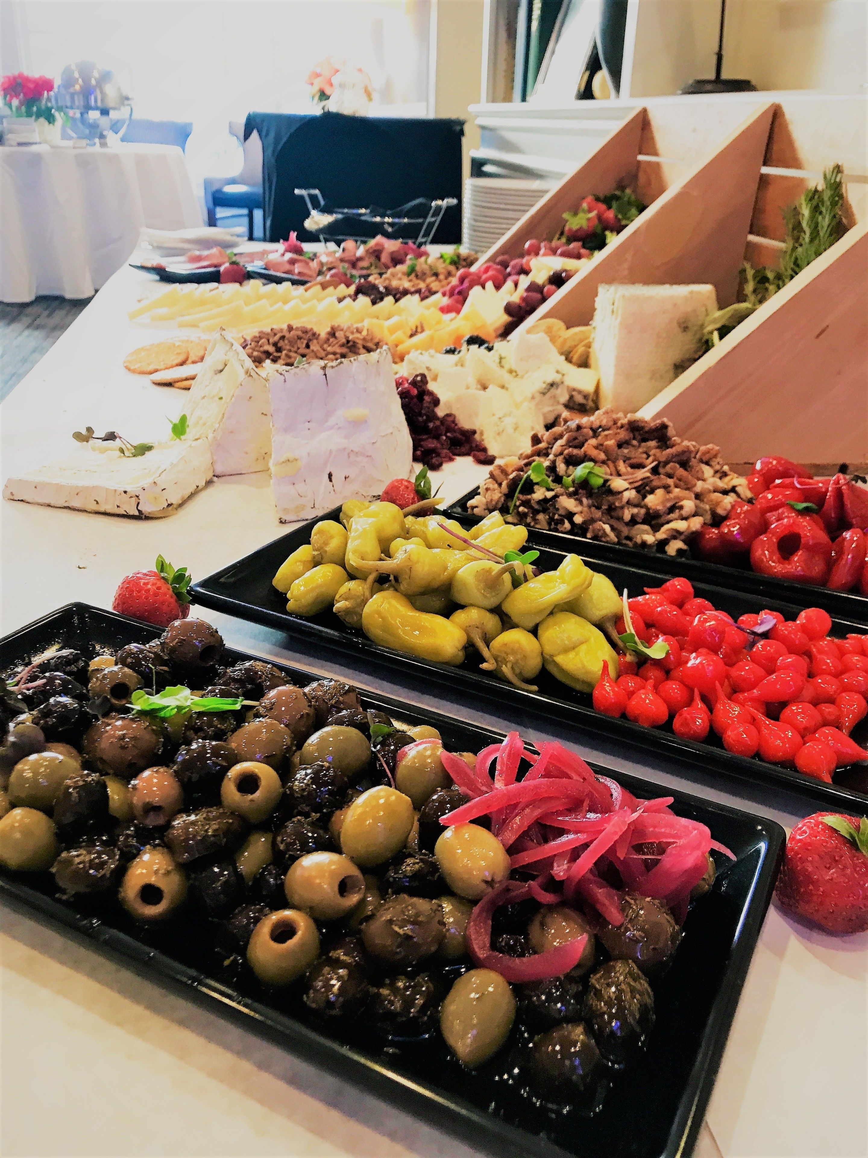 A buffet table with various food items including cheese, olives, and fruits.