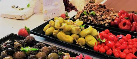 A buffet table with various food items including cheese, olives, and fruits.