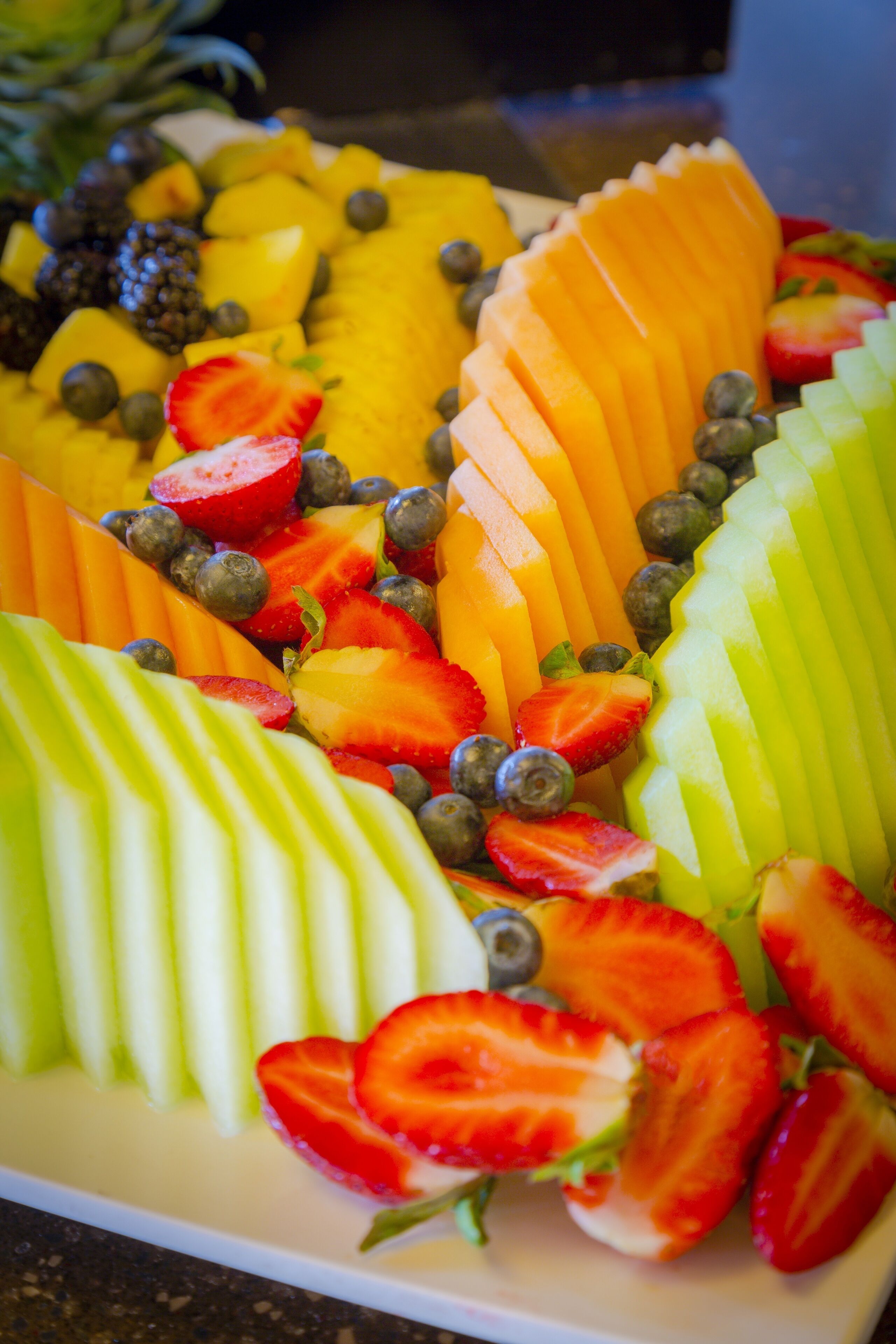 Een fruitschaal met diverse gesneden vruchten en bessen.