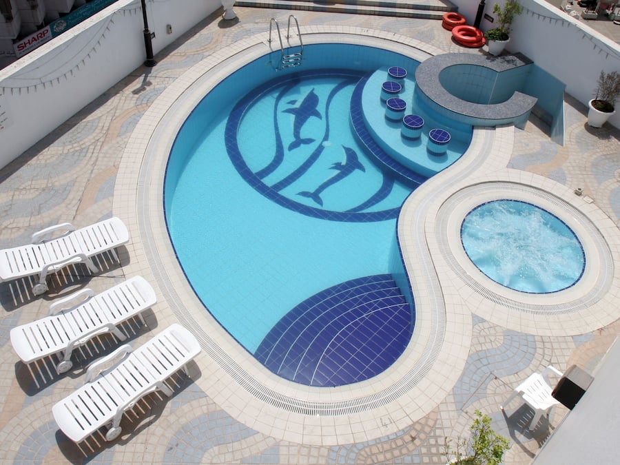 Una piscina al aire libre, sombrillas, sillones reclinables de piscina