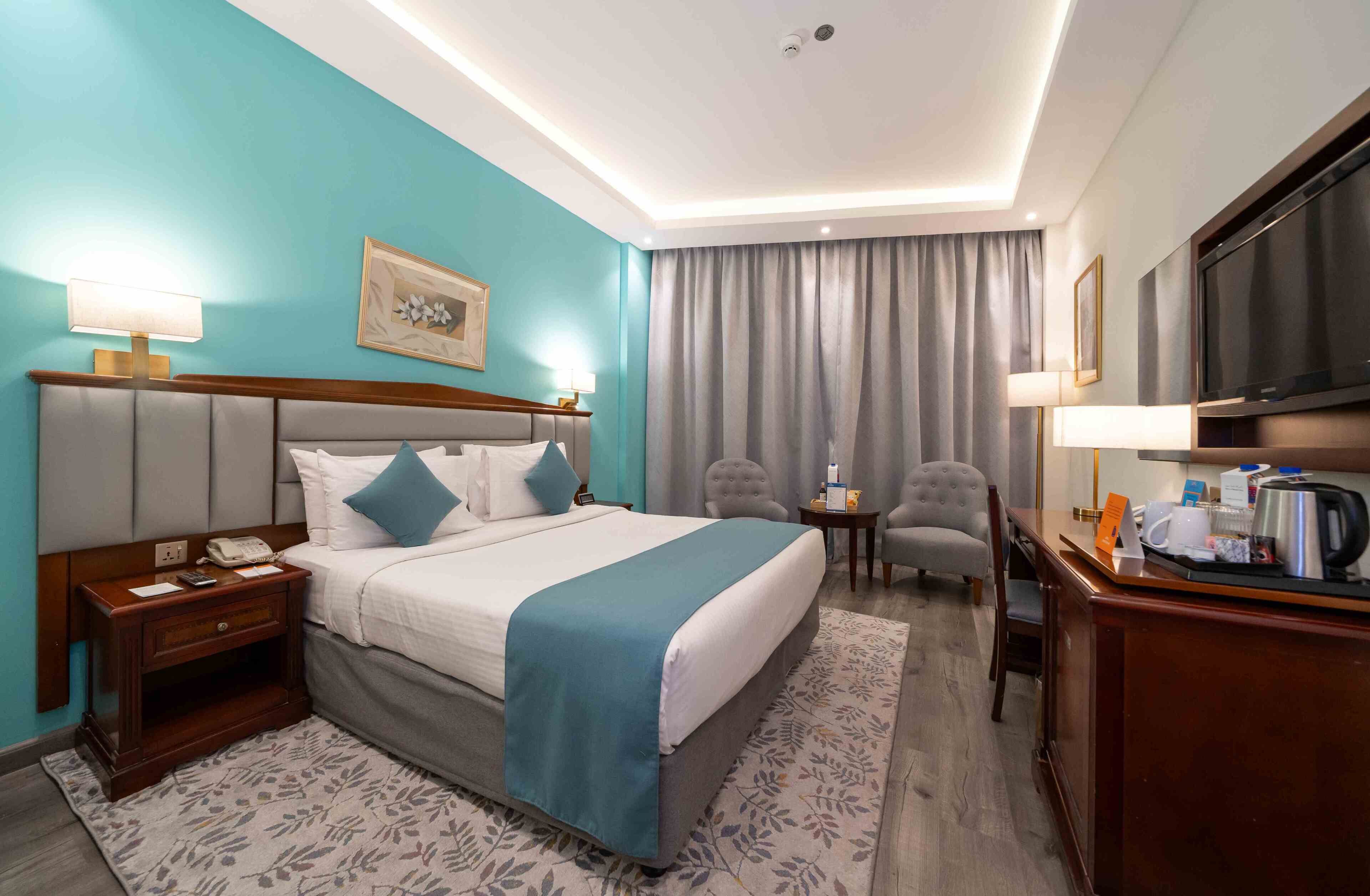Une chambre d’hôtel comprenant un lit, des lampes de chevet, un bureau avec une machine à café, une télévision et une chaise.