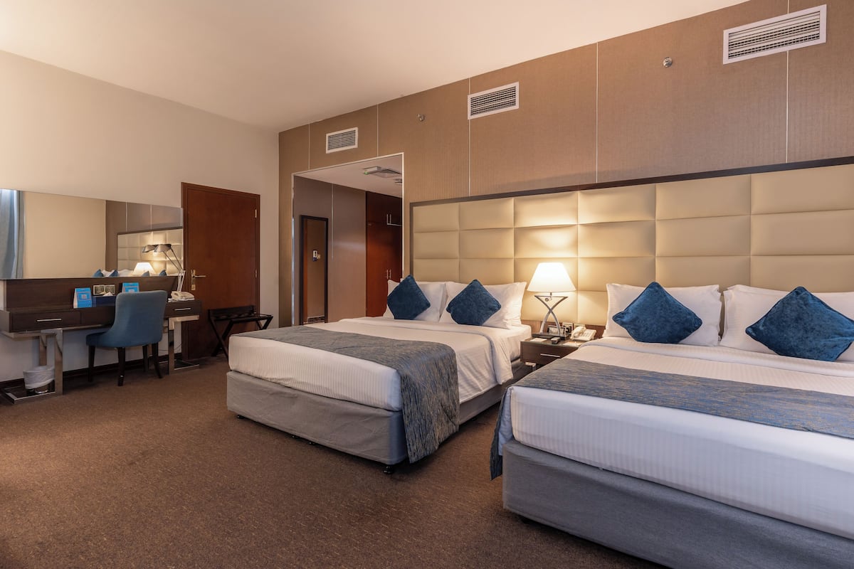 Een hotelkamer met twee bedden, een bureau en een stoel.