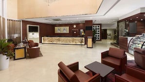 Un hall d'hôtel comprenant un comptoir d'accueil, un espace salon et un présentoir de desserts.