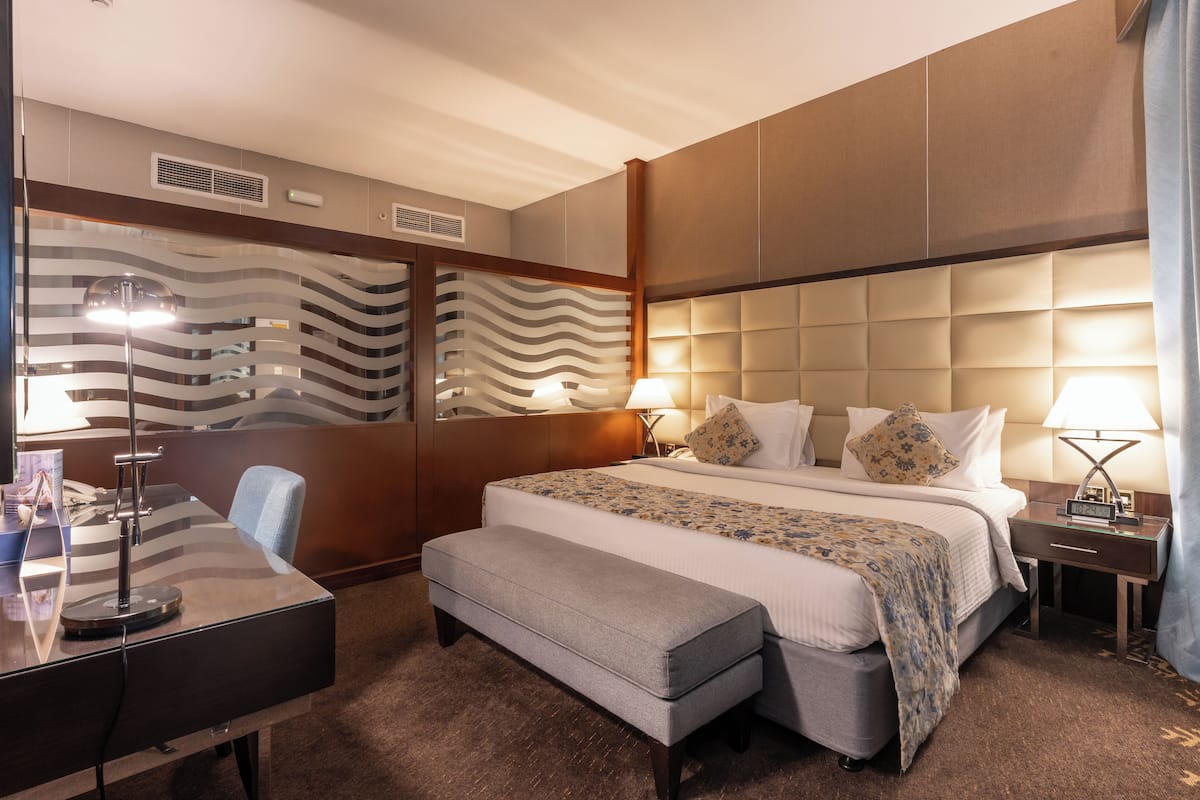 Een hotelkamer met een groot bed, een bureau, een bankje en een muur met een golvend patroon.