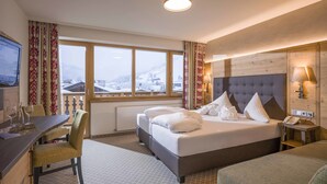 Une chambre d’hôtel avec un lit, un bureau et une chaise. Il y a une fenêtre donnant sur un paysage enneigé.