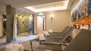 Une salle de spa équipée d’une table de massage, de serviettes, d’une douche en verre et d’une fresque murale représentant un paysage de montagne.