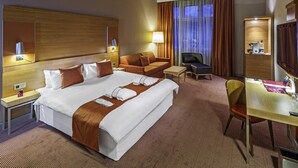 A hotel room with a large bed, a desk, a chair, a sofa, and a TV. - Mercure Ostrava Center Hotel (Ostrava)