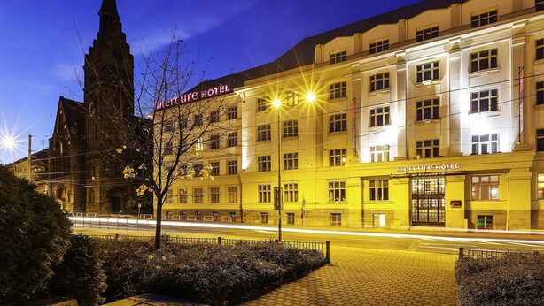 Un hotel con una torre destacada, un edificio grande con muchas ventanas y una entrada bien iluminada.