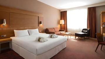 Una habitación de hotel con una cama grande, un escritorio, una silla y un sofá.
