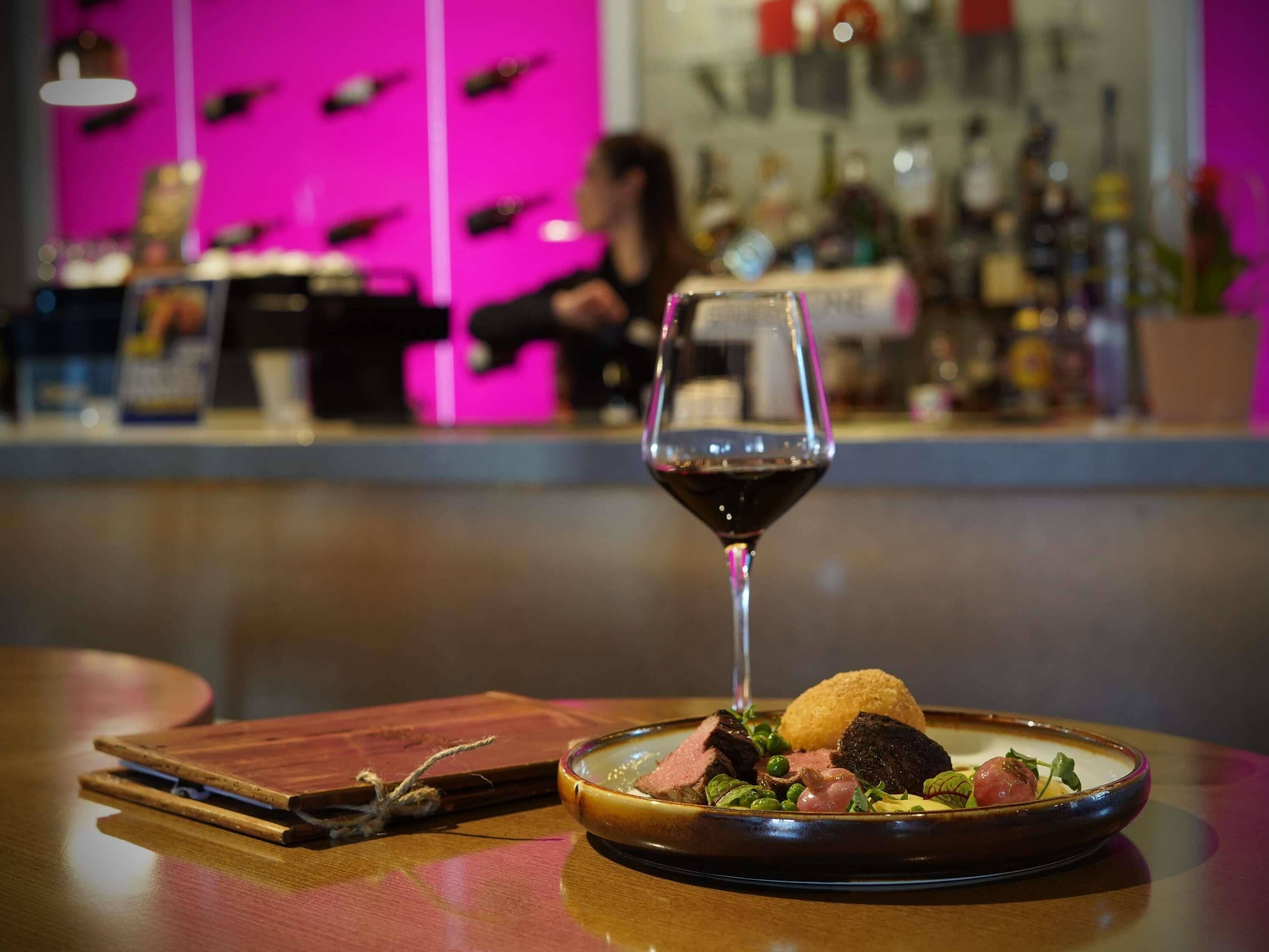 Une table à manger avec une assiette de nourriture et un verre à vin.