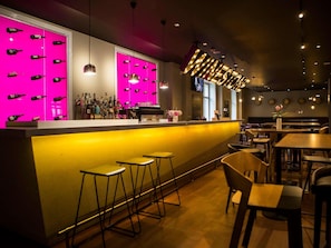 Un espace bar avec des tabourets, un comptoir et un panneau lumineux au néon.
