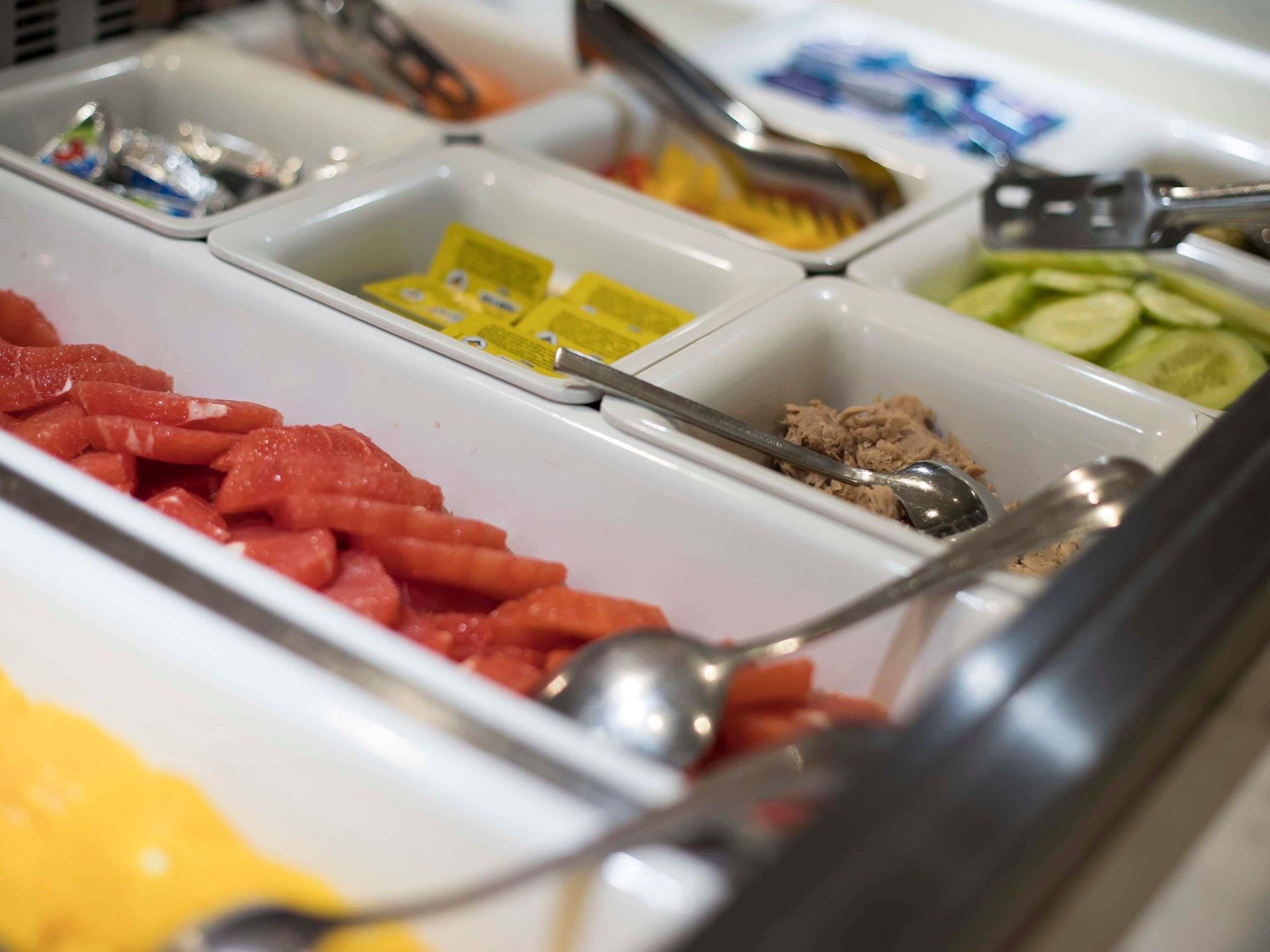 A buffet with various food items in separate containers.