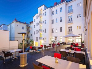 An outdoor patio area with tables and chairs, surrounded by buildings. - Mercure Ostrava Center Hotel (Ostrava)
