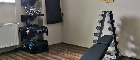 A gym with a bench, kettlebells, and dumbbells.