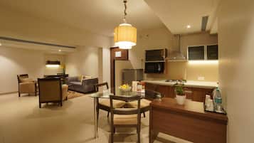Una sala moderna con una mesa de comedor de vidrio, un sofá y una cocina con microondas y estufa.