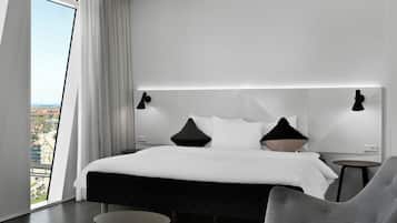 A modern hotel room with a large bed, two bedside tables, a chair, and a view of the city.