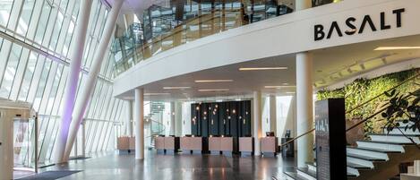 A modern interior with a glass facade, a staircase, and a reception desk labeled "BASALT".