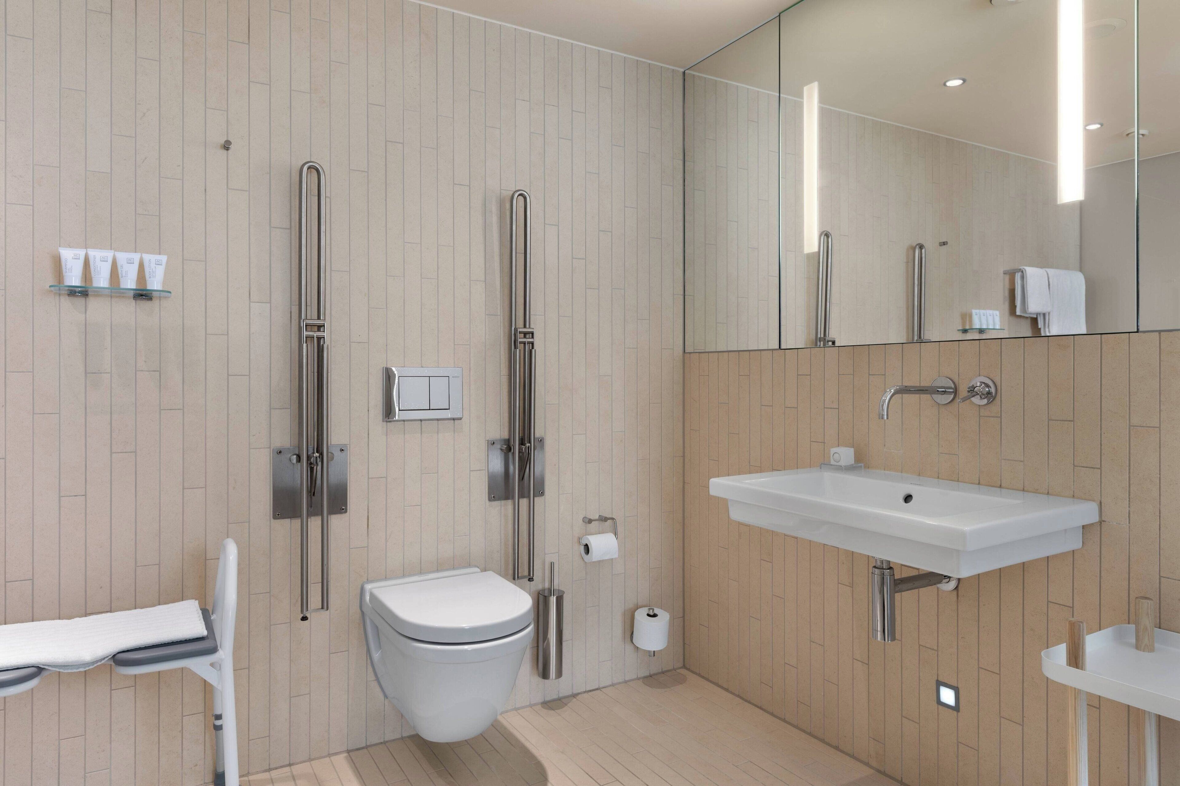 Een moderne badkamer met toilet, hygiëneschuimer en wastafel.