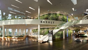A modern interior with a central staircase, seating areas, and a wall with greenery.