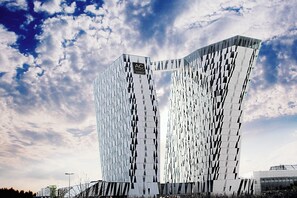 A modern hotel with a distinctive geometric facade and a prominent logo at the top. - AC Hotel by Marriott Bella Sky Copenhagen (Copenhagen)