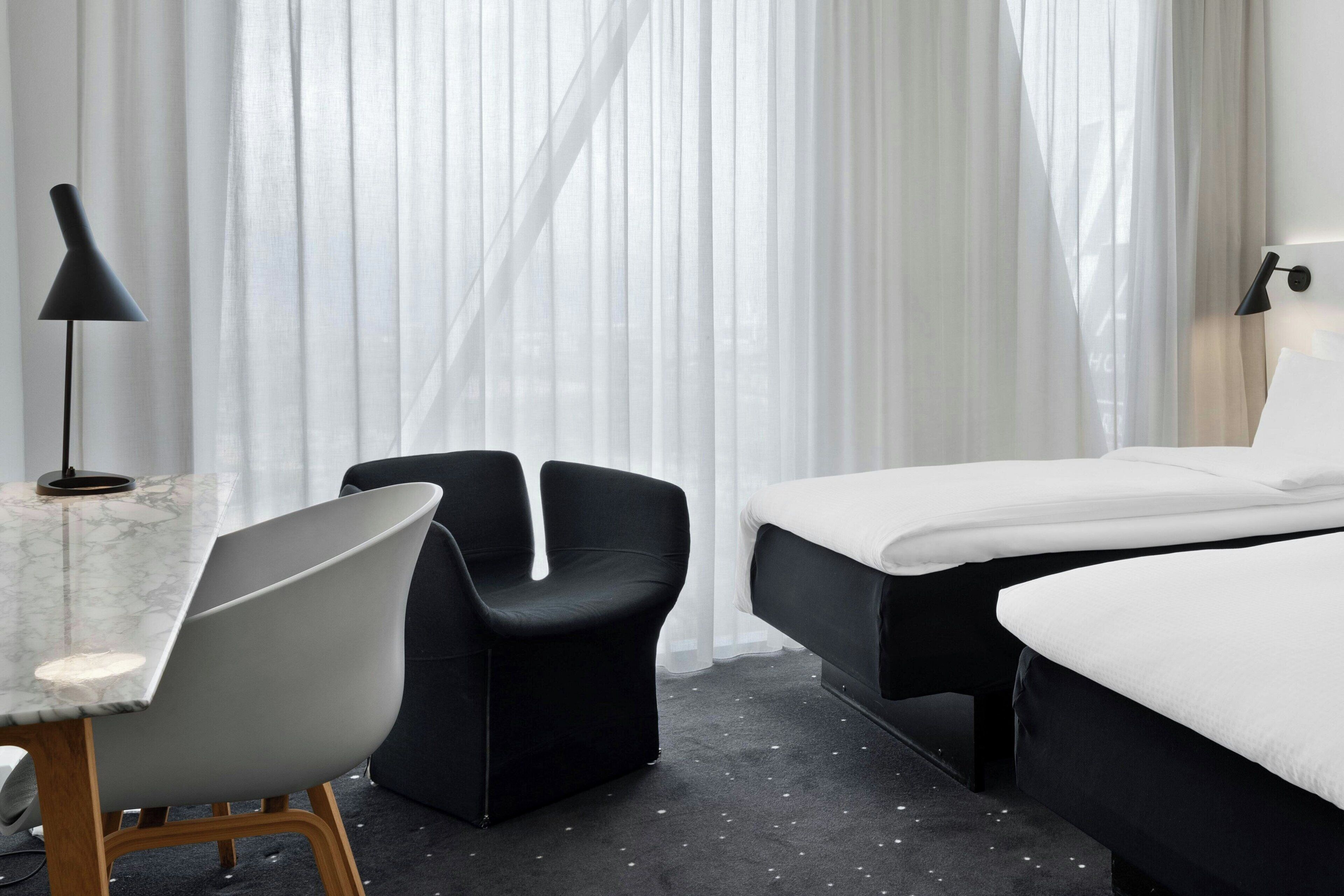 Una habitación de hotel con una cama, un escritorio con silla y una lámpara.