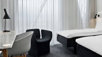 Una habitación de hotel con una cama, un escritorio con silla y una lámpara.
