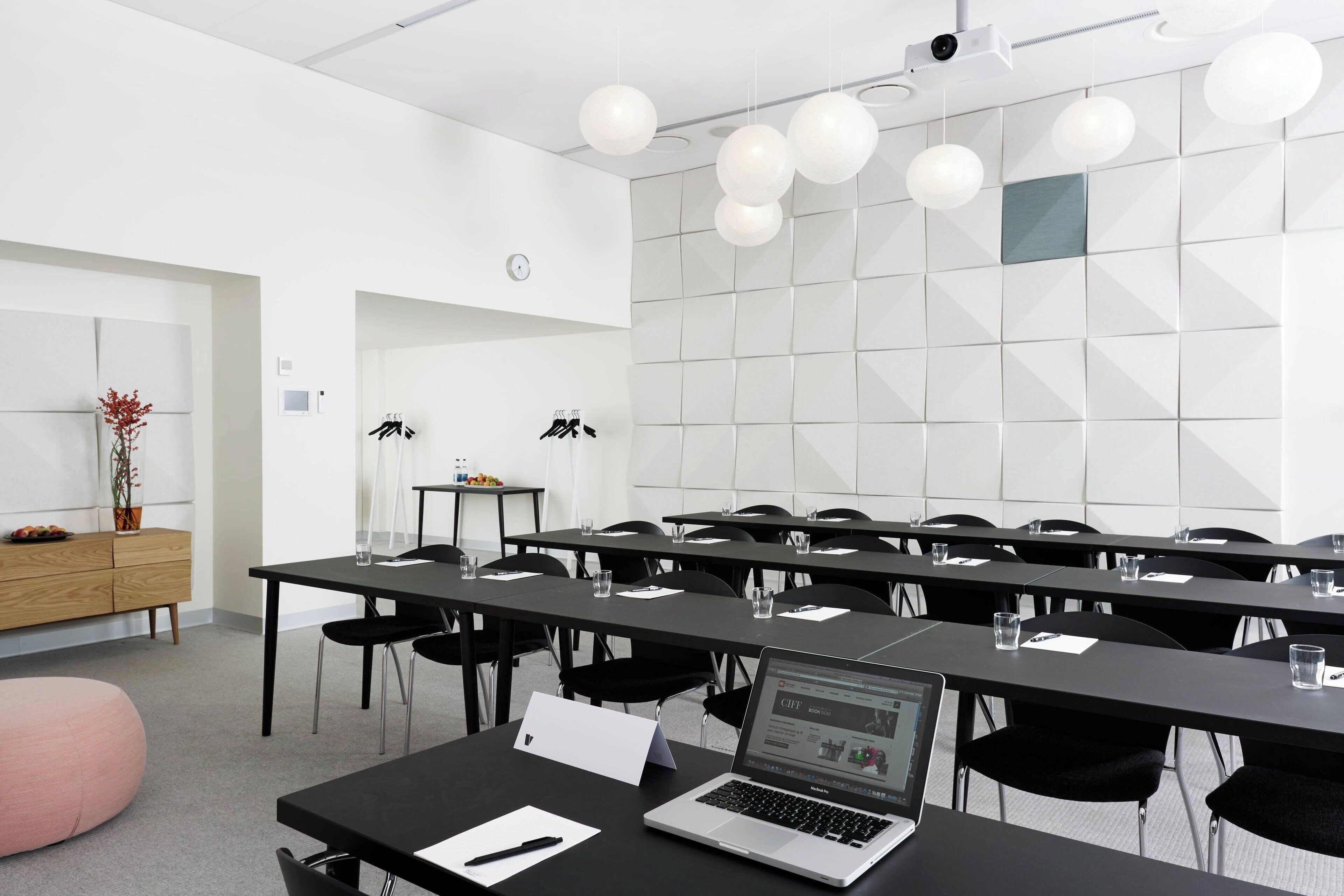 A conference room with long tables, chairs, and a laptop on one table.