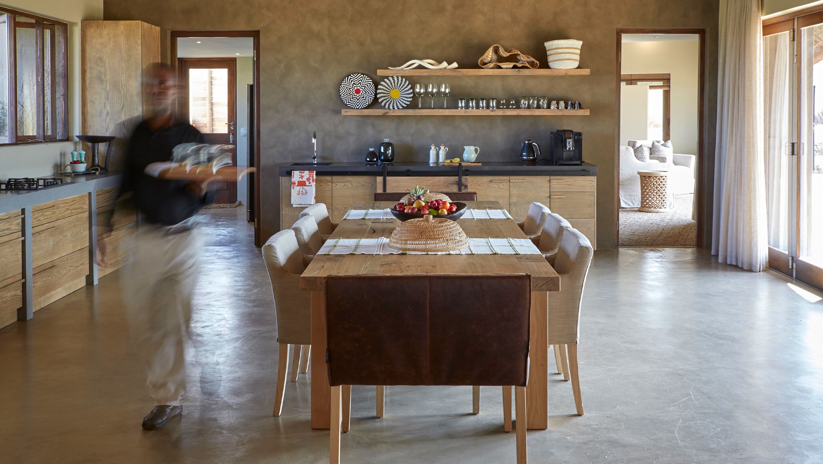 Una cocina moderna con armarios de madera, una mesa de comedor con sillas y una cafetera.