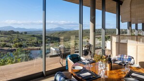 Un coin repas avec une table dressée pour deux personnes, offrant une vue sur un paysage magnifique.